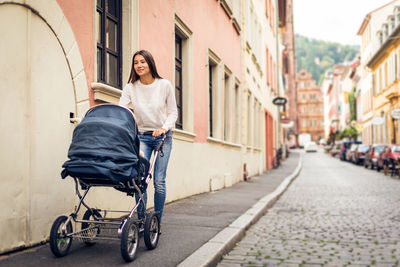 Full length portrait of woman on footpath in city