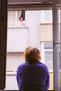 Rear view of woman looking through window