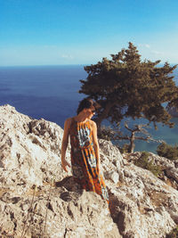 Young woman standing by sea against clear sky