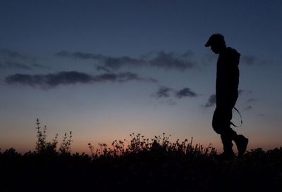 Silhouette of people standing on field at sunset