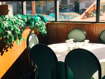 Empty chairs and table against window