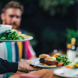 Cropped hand of waiter keeping food on table in restaurant