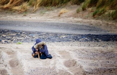 Person posing with dog on sand at beach