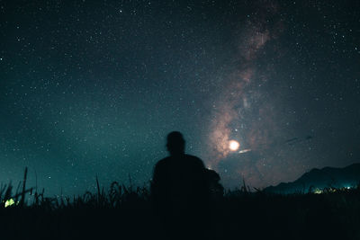 Rear view of silhouette man against sky at night