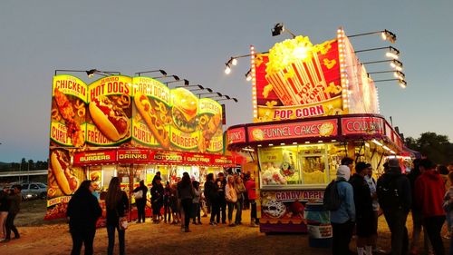 People at amusement park against sky at night