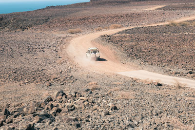 A tourist safari vehicle seen driving in the desert against the background of lake turkana in kenya