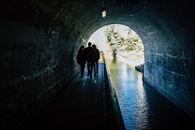 Rear view of silhouette people walking in tunnel