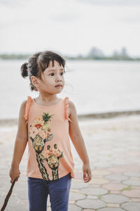 Young woman standing by sea against sky