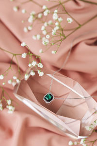 Close-up of jewelry with flowers against textile