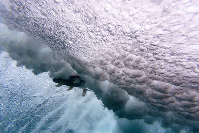 Low angle view of surfboard amidst waves breaking undersea at maldives