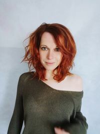 Portrait of mid adult woman with redhead standing against wall at home