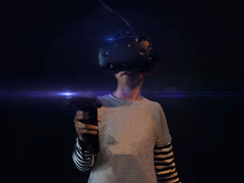 Young asian boy holding and wearing vr game set in the black background. selected focus.