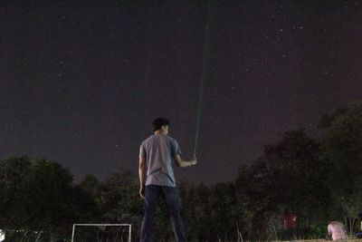 Rear view of man standing against sky at night