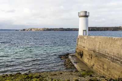 Lighthouse by sea against sky