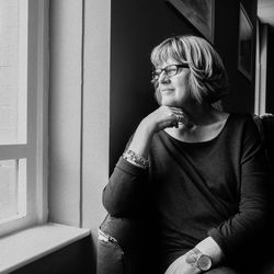 Thoughtful woman looking through window while sitting on chair at home