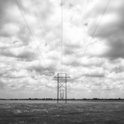 Electricity pylon on field against sky