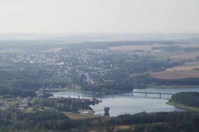 Scenic view of river by cityscape against sky