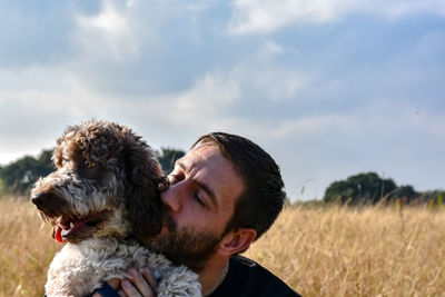 Man with dog on field against sky