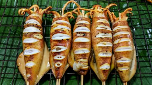 High angle view of grilled squids on metal grate at market stall