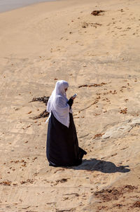 High angle view of woman using phone while walking at beach