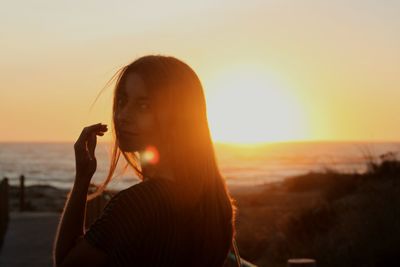 Portrait of woman at beach against sky during sunset