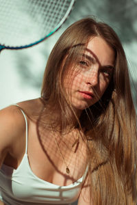 Close-up portrait of beautiful young woman holding racket