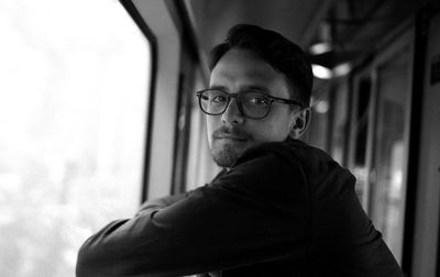 Portrait of young man by window in train
