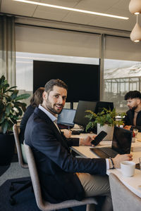 Side view portrait of businessman sitting on chair at desk in coworking office