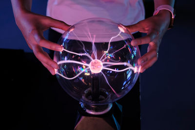 Close-up of hand holding crystal ball against black background