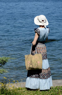 Rear view of woman standing by lake