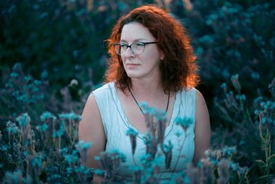 Mature woman standing between plants looking away