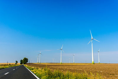 Wind turbines on field against blue sky