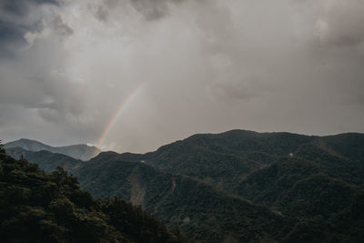 Scenic view of rainbow over mountains against sky