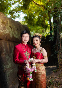 Smiling portrait of newlywed couple holding flowers