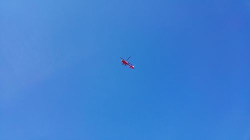 Low angle view of red paragliding against clear blue sky