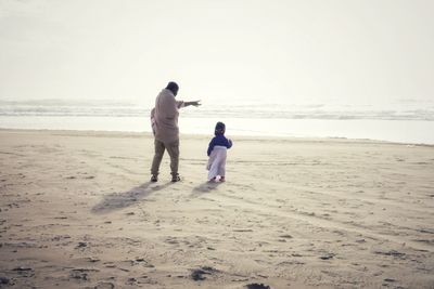 Rear view of couple walking on beach