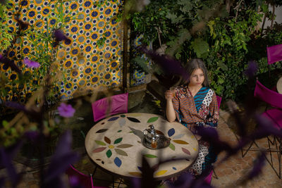 Full length of cute girl sitting on plant