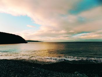 Scenic view of sea against cloudy sky during sunset