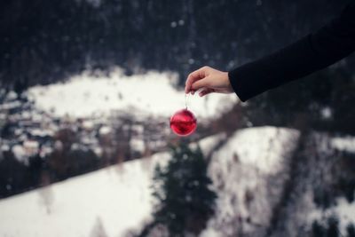 Cropped hand holding red bauble during winter