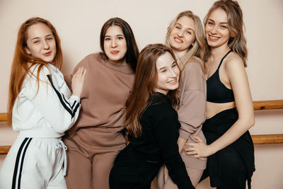 Multiracial group of girls standing against the wall, sporty happy women laughing, talking while