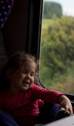 Close-up of cute girl sitting on window