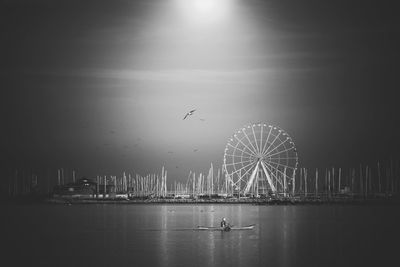 View of ferris wheel in sea against sky