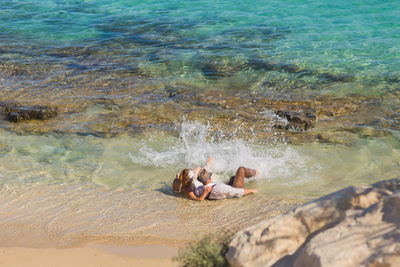 High angle view of woman relaxing on rock by sea