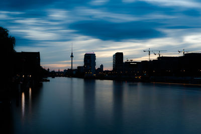 River by buildings against sky at dusk