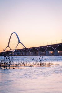 Arch bridge over river against sky during sunset