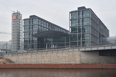 Modern buildings by river against sky in city