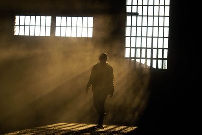 Rear view of silhouette man walking in building