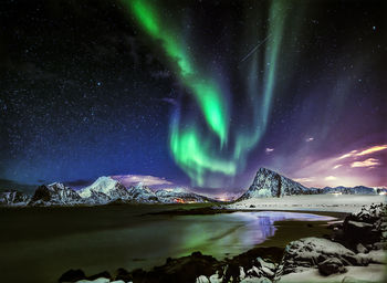 Scenic view of illuminated snowcapped mountains against sky at night