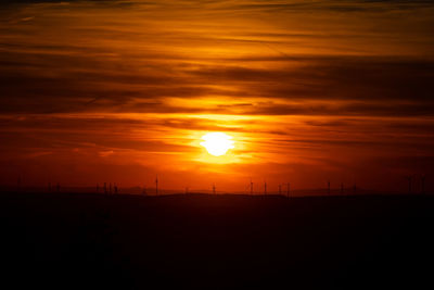 Scenic view of silhouette field against orange sky