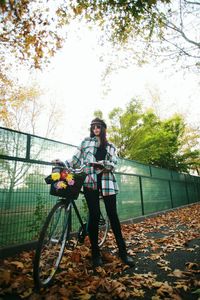 Full length of smiling woman with bicycle against sky